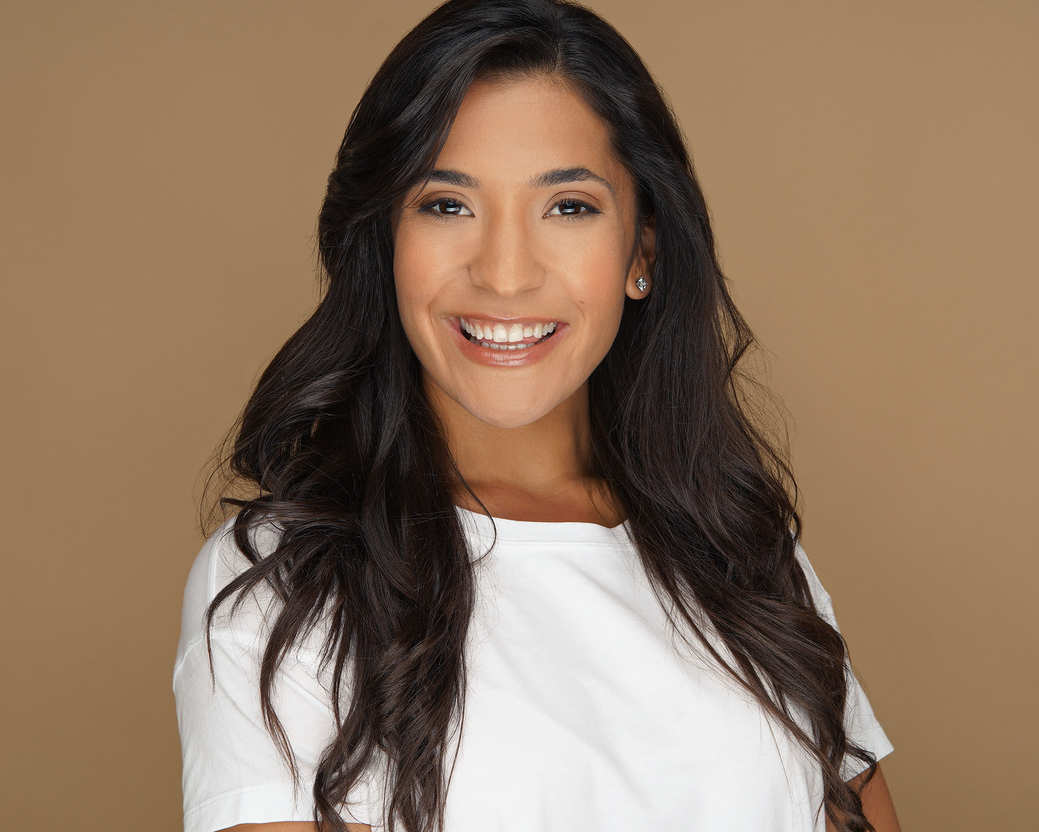 Shira Math smiling in a white t-shirt against a warm neutral backdrop